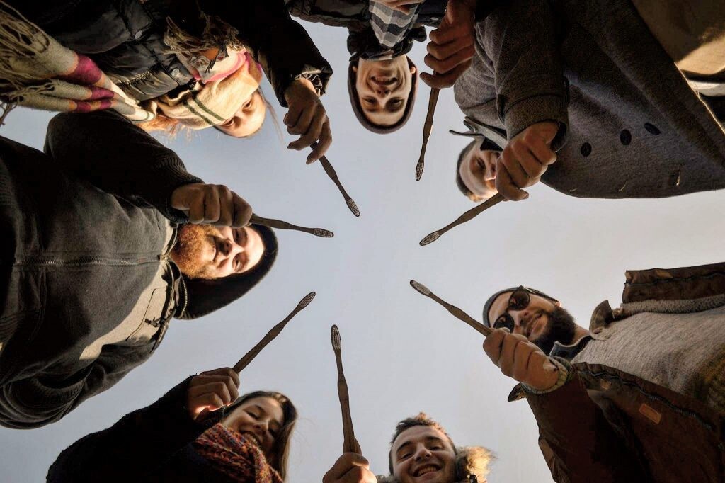 Propagačná fotografia, na ktorej sú ľudia stojaci v kruhu a držia bambusové kefky Mobake.