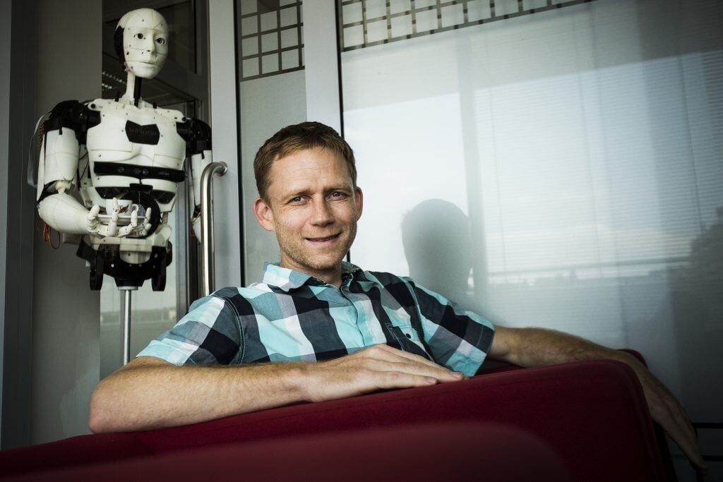 Michal Hrabovec, šéf spoločnosti Anasoft, sedí v kresle a za ním je robot. 