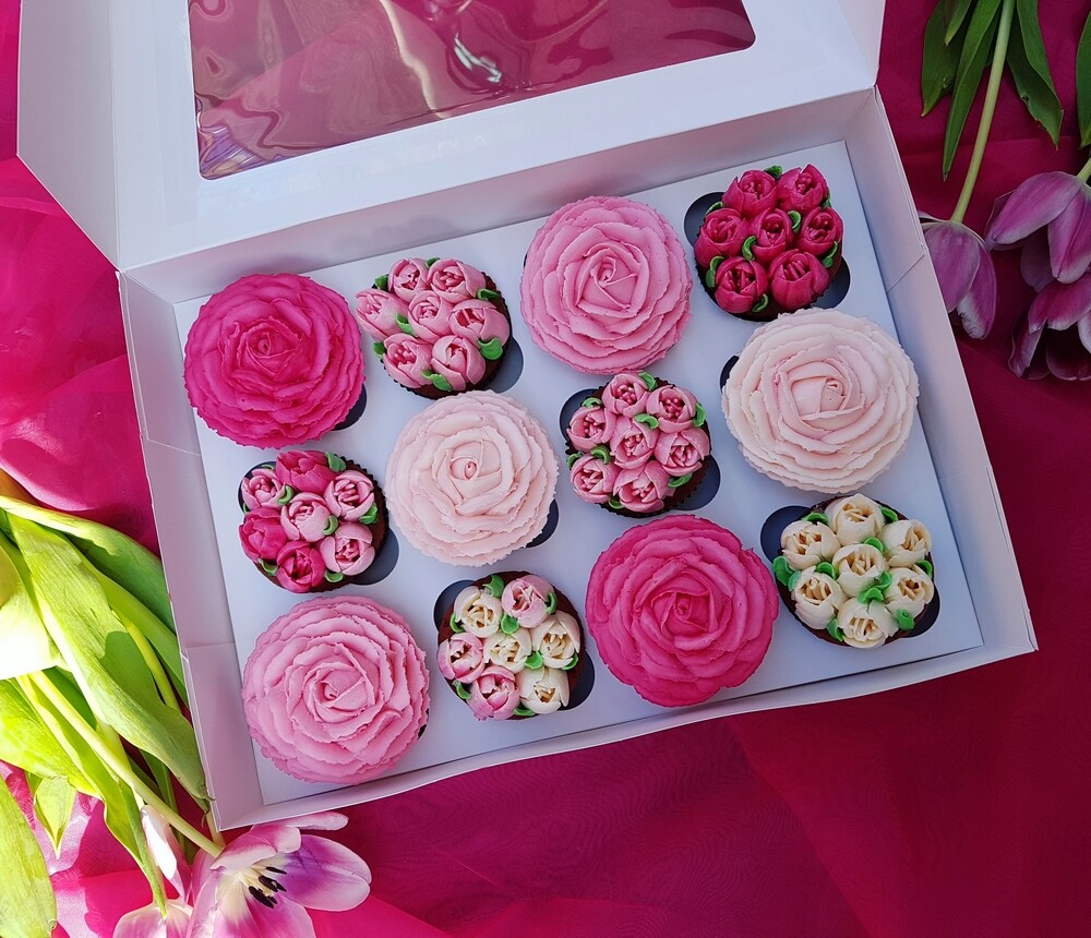 Krabica naplnená cupcakeami s vrchnými kvetmi v ružovej farbe. 