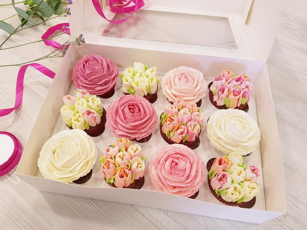 Škatuľa, v ktorej sú cupcaky pokryté krémovými kvetinami, ktoré robí Martina z Cupcake Roses.