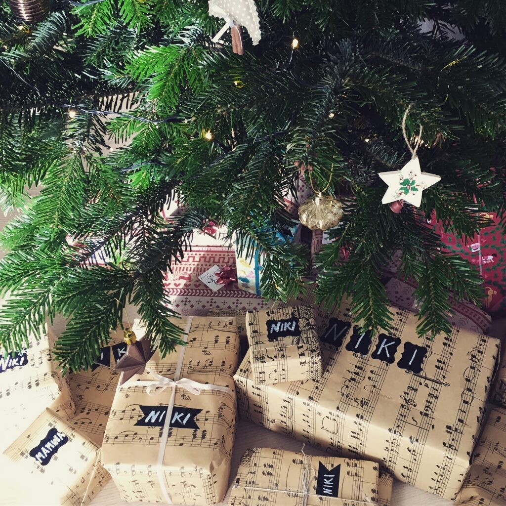 Darčeky, zabalené v papieri s notovým motívom, pod vianočným stromčekom.